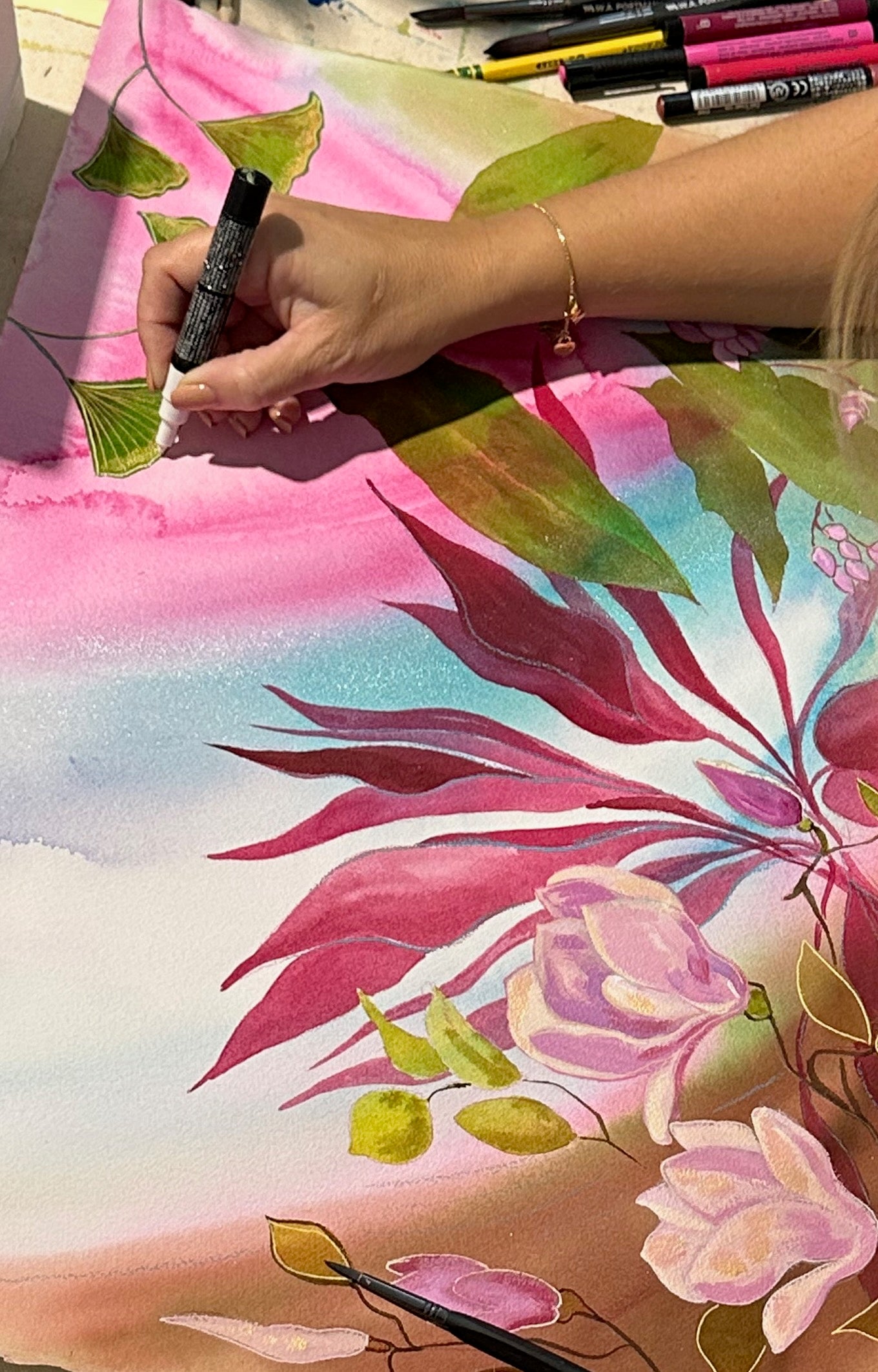 The artist Tania Herrera's hand holding a marker, meticulously adding details to a mixed media contemporary artwork, showcasing her creative process and artistic expression at Aquamarine Design Studio.